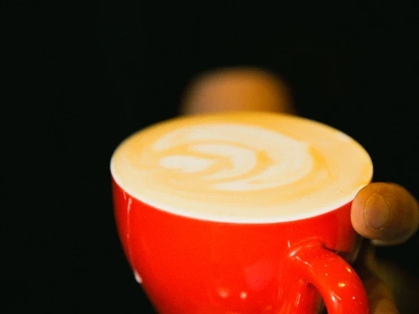 Taza roja con café de especialidad y latte art