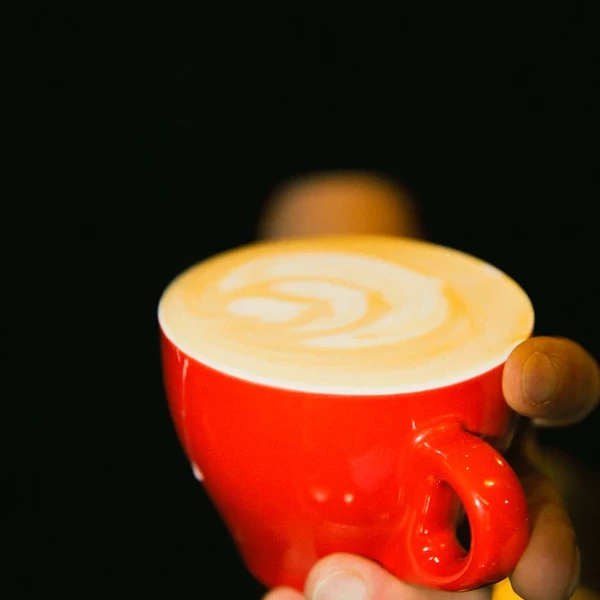 Taza roja con café de especialidad y latte art